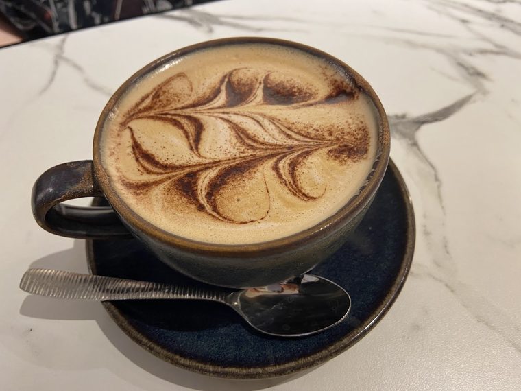 Cappuccino in a dark ceramic cup on a marble table