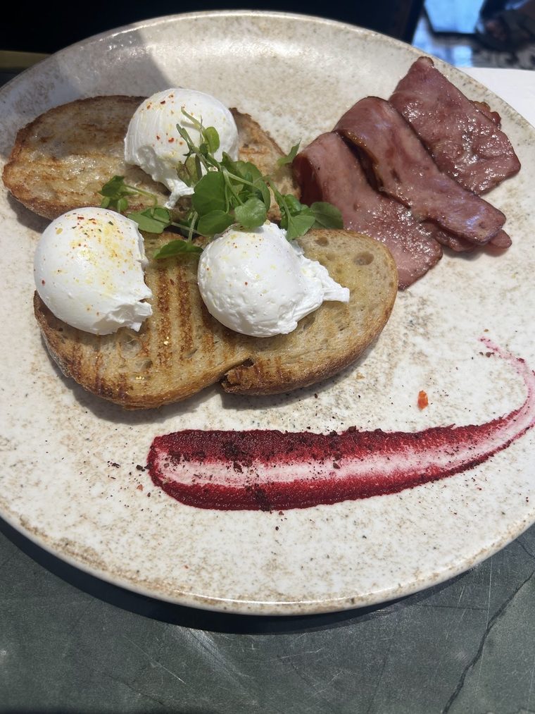 Two poached eggs on toasted sourdough with bacon and microgreens